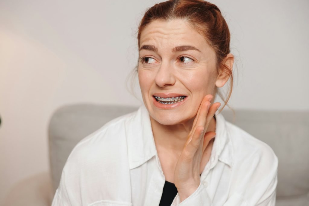 Portrait of red-haired mature woman suffering from pain due to braces