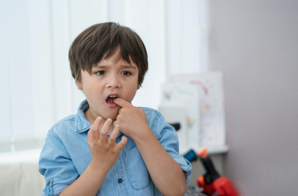 young kid putting finger in his mouth feeling hurt from falling first tooth,Emotional child boy