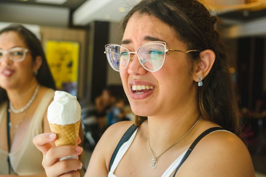 young woman with dental sensitivity, her teeth hurt from eating ice cream.